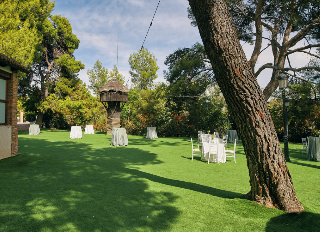Jardín del Bosque de Palacio del Negralejo con árboles y mesas de cóctel